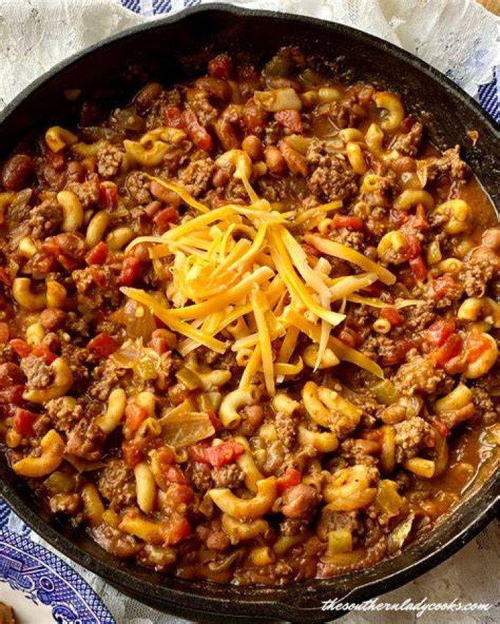 Chili mac in a skillet with a wooden spoon.